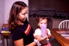 Image of a mother holding a glass to her daughter's mouth